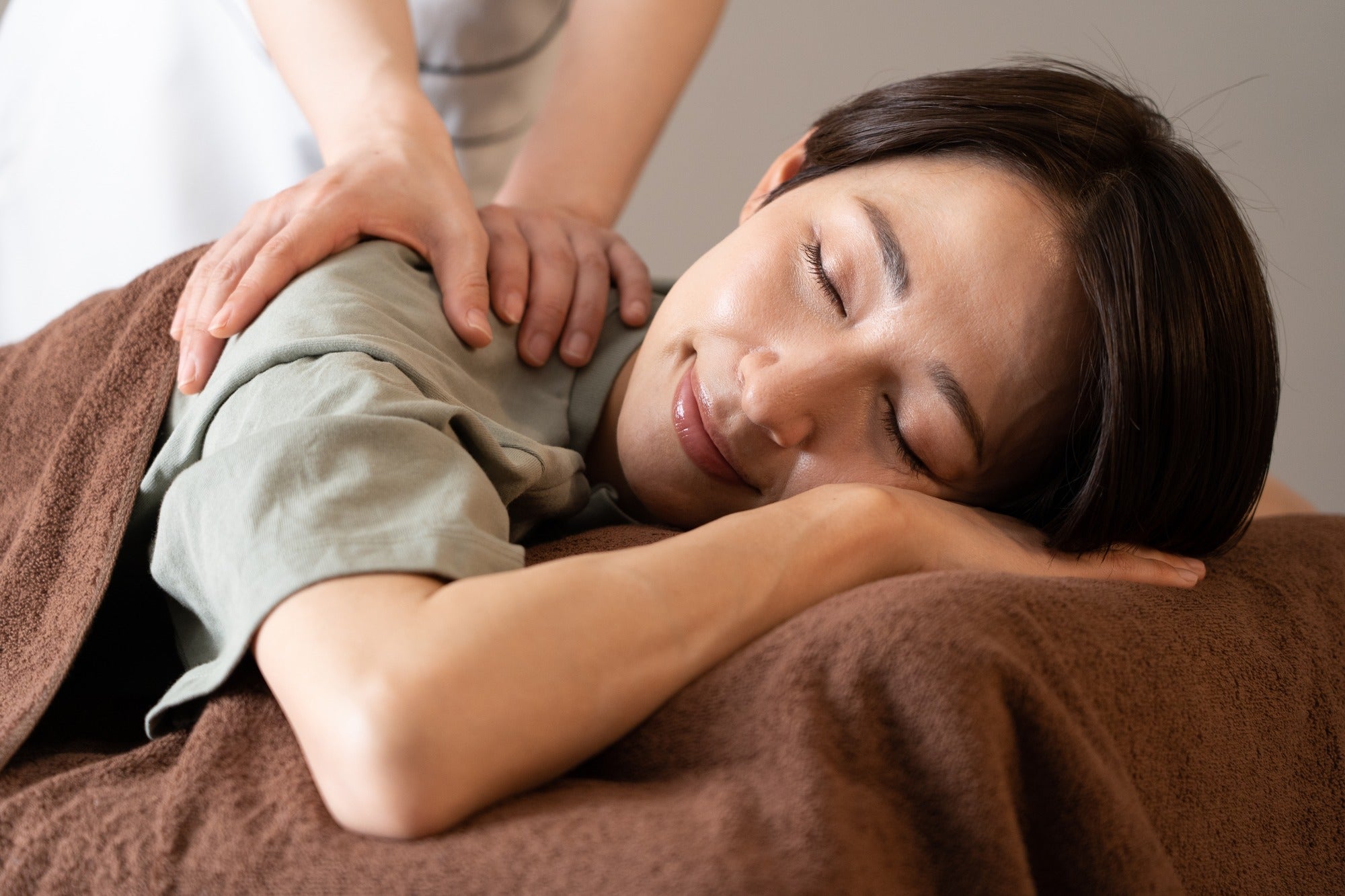 Home spa session: Smiling woman enjoying a professional massage therapy at home.