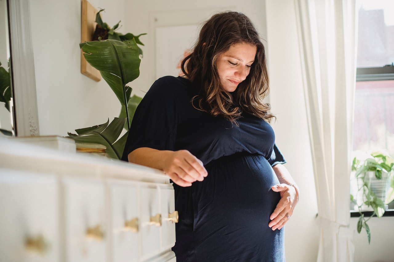  Pregnant woman holds her belly happily thanks to massage therapy.